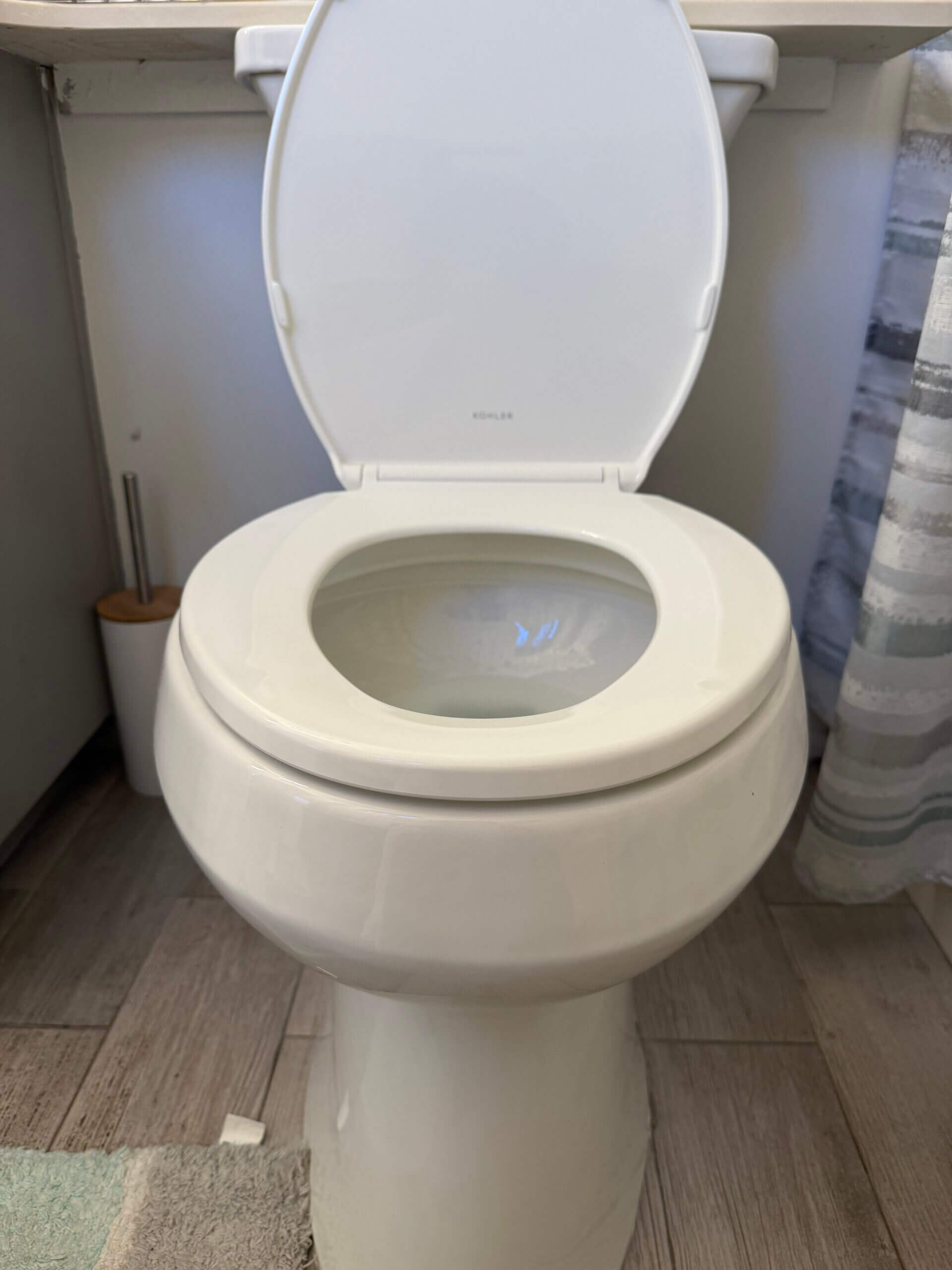 A newly installed white Kohler elongated toilet fixture inside a residential bathroom remodel completed by SDAC Plumbing.